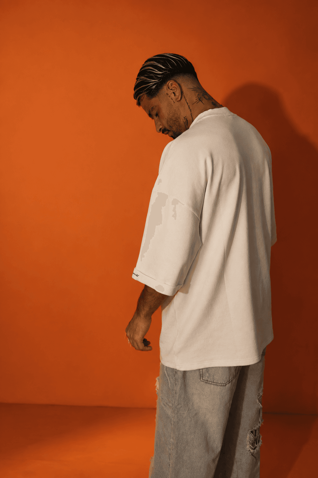 ORS LABEL look — cream oversized tee and light-wash ripped jeans, orange backdrop